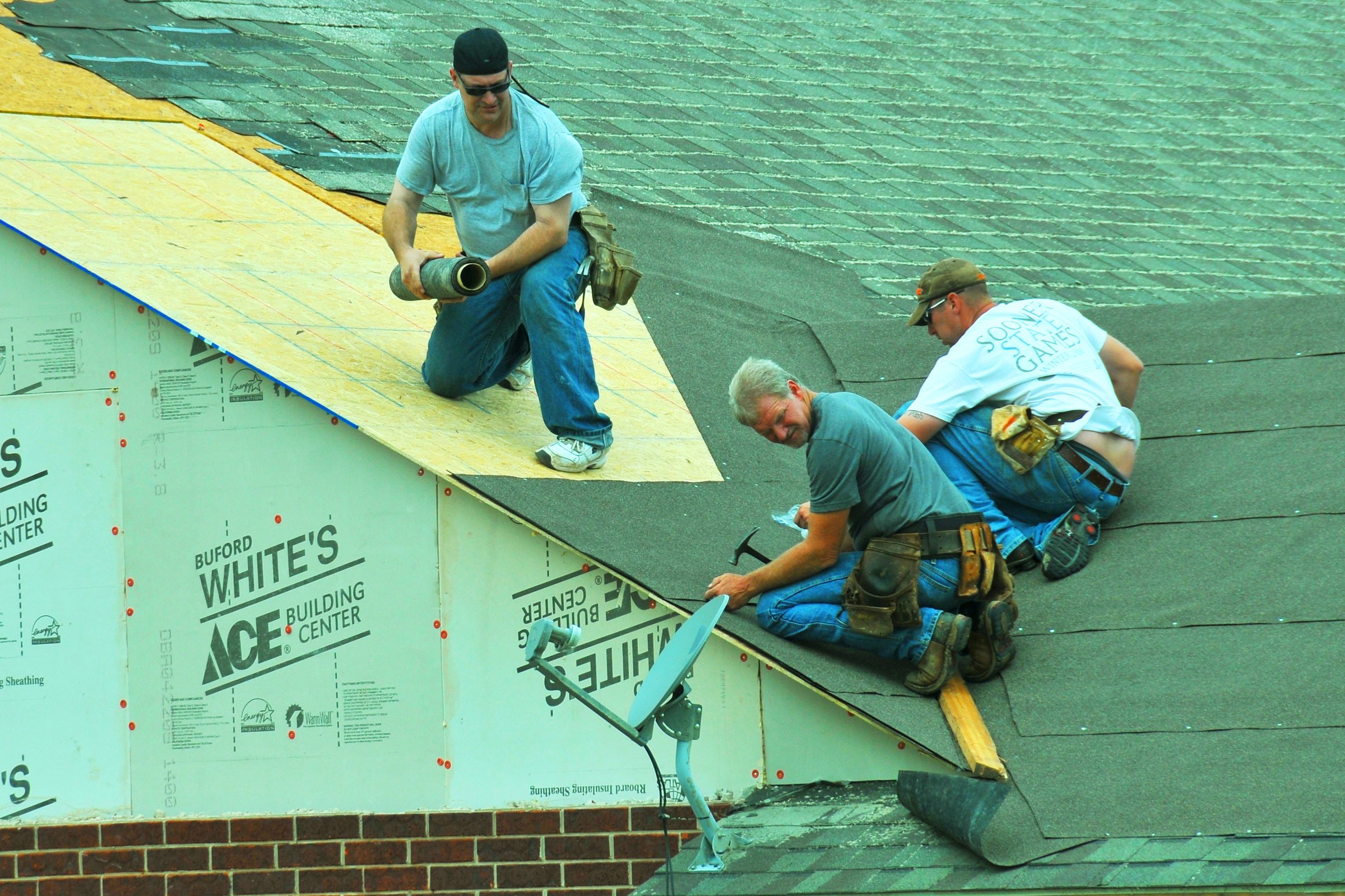 Storm-damaged roofing under active repair after high-wind impact.